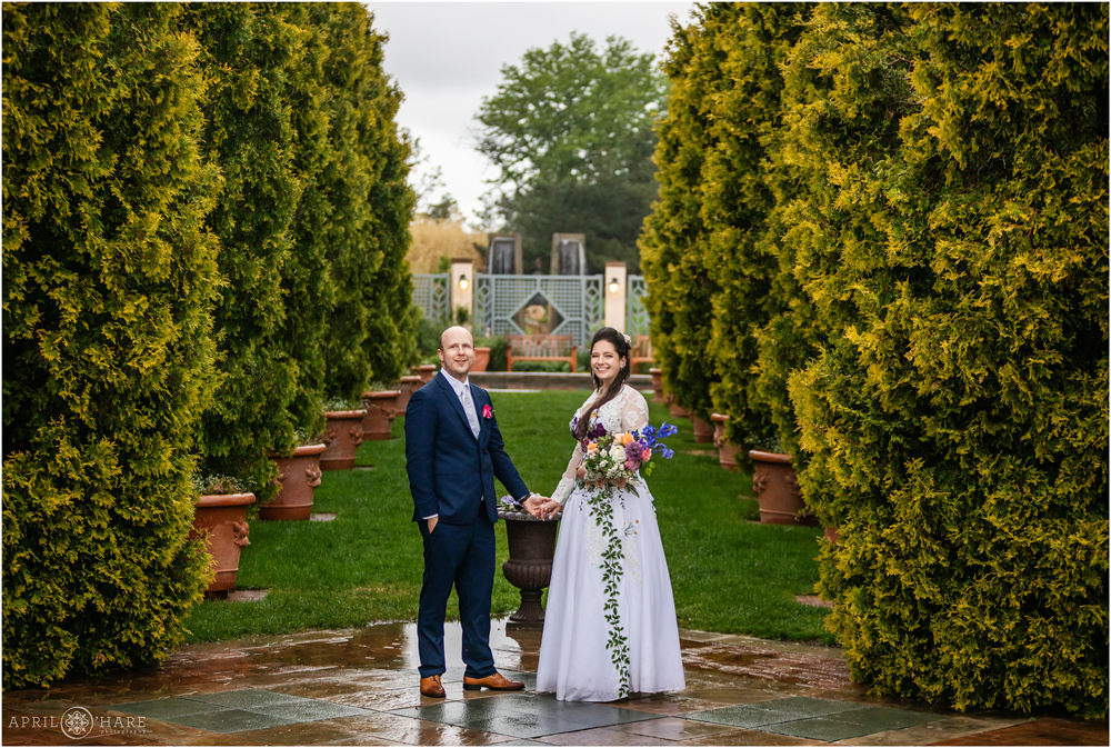 Bride and groom hold hands in front of the beautiful romantic gardens area of Denver Botanic Gardens