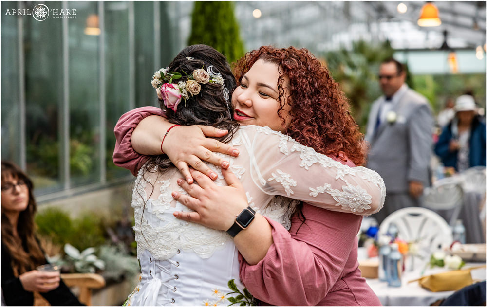 Candid moments guests hug bride inside the Orangery at Denver Botanic Gardens