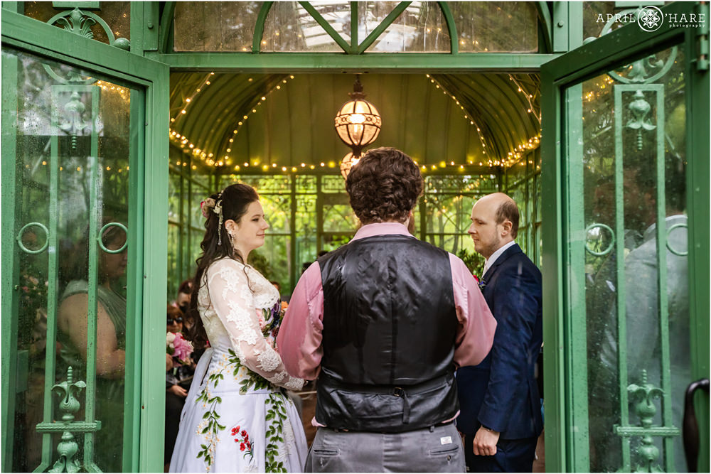 View of couple getting married inside the historic green solarium on a wet rainy wedding day in Denver
