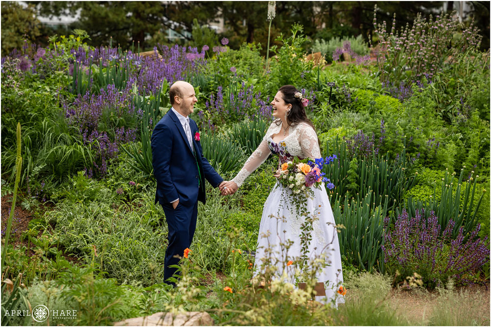 Bride and groom laugh together in front of a pretty purple floral garden at Denver Botanic Gardens on a rainy day