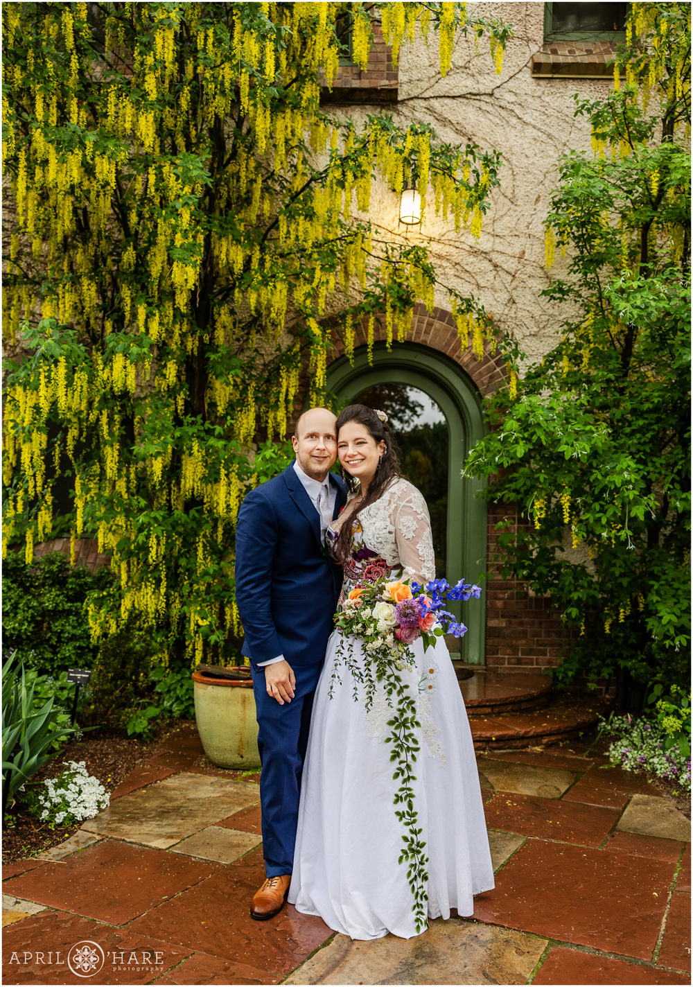 Pretty yellow drooping flowers on a tree in the backdrop for bride and groom portrait in the courtyard outside of the Richard Crawford Campbell House at Denver Botanic Gardens