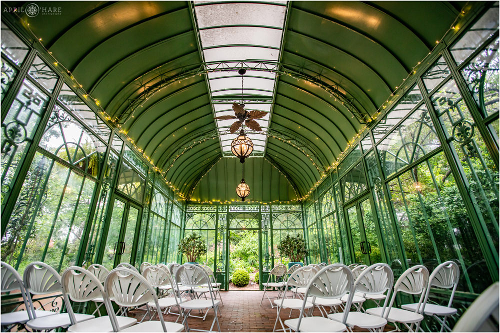 Wide angle view of the inside of the historic green solarium at Woodland Mosaic Garden set up for a wedding on a rainy day in Colorado