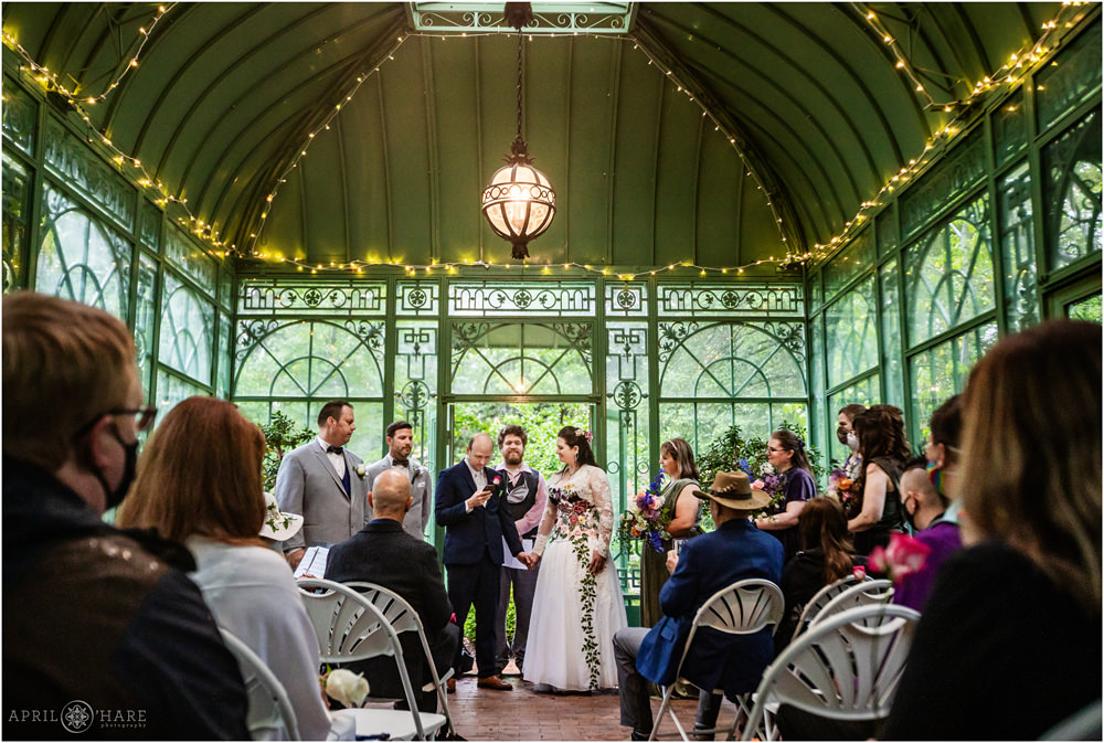 Wide angle photo of bride and groom saying their vows inside the Green Solarium at Denver Botanic Gardens in Colorado