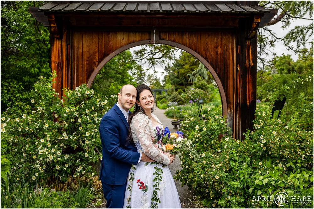 Gorgeous wedding photo for a couple standing in front of circle gate at Denver Botanic Gardens with roses framing them