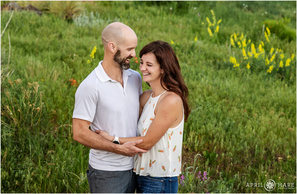 Cute photo of a couple laughing together in the wildflowers at East Mount Falcon in Colorado
