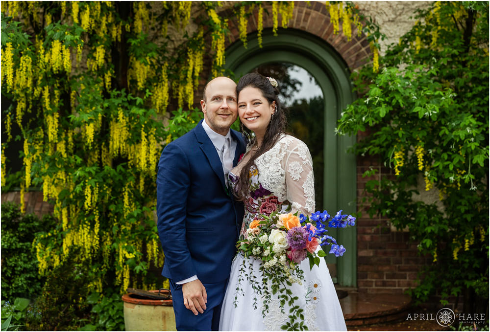 Beautiful springtime wedding photo with pretty yellow flowers hanging from tree in the backdrop