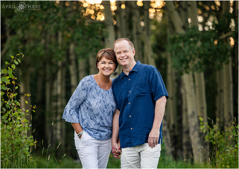Couple wearing blue and white holding hands in an aspen tree forest in Evergreen Colorado