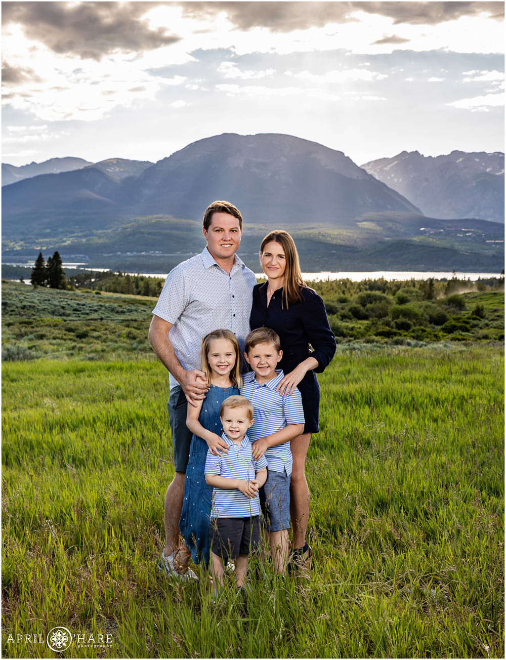 A family of 5 with 3 young children pose for a family picture in front of a pretty mountain view in Colorado