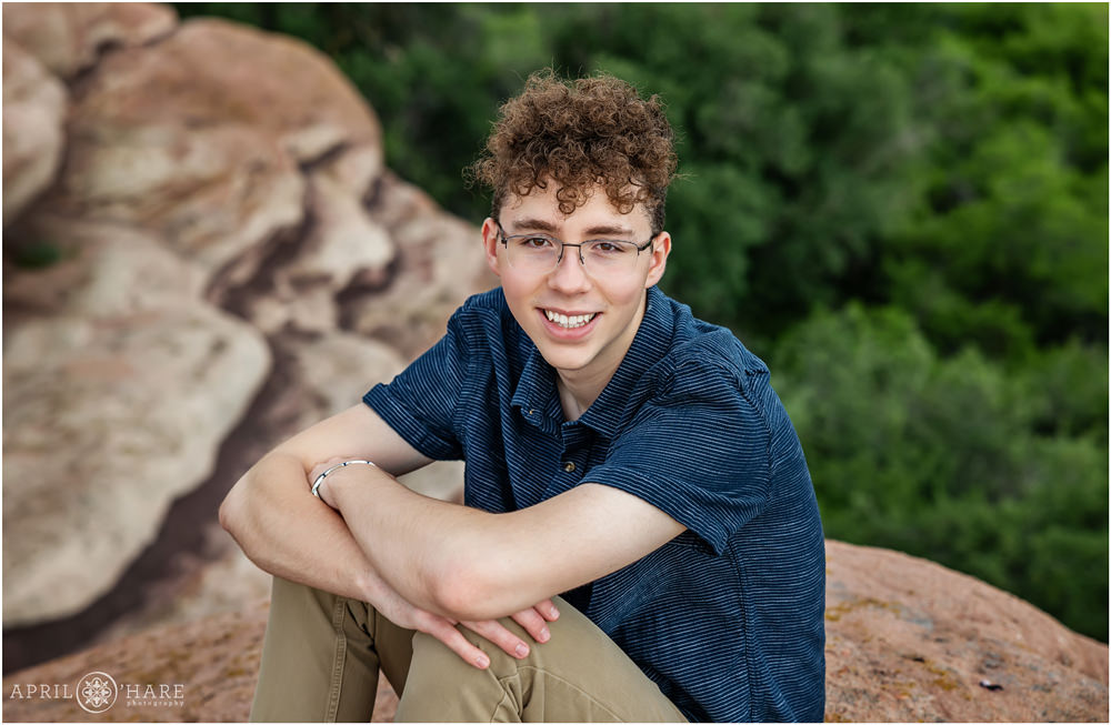 High school senior boy wearing blue shirt and glasses is photographed in his awesome Ken Caryl Neighborhood in Southwest Denver