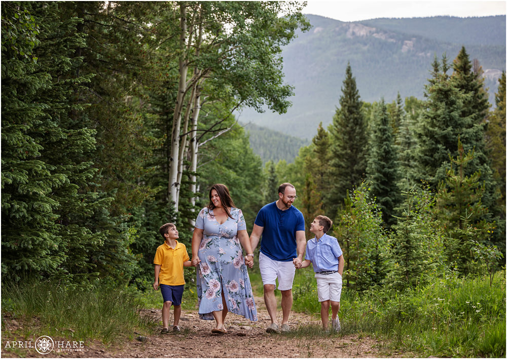 Family walks down a path together in the mountains of Evergreen Colorado during summer