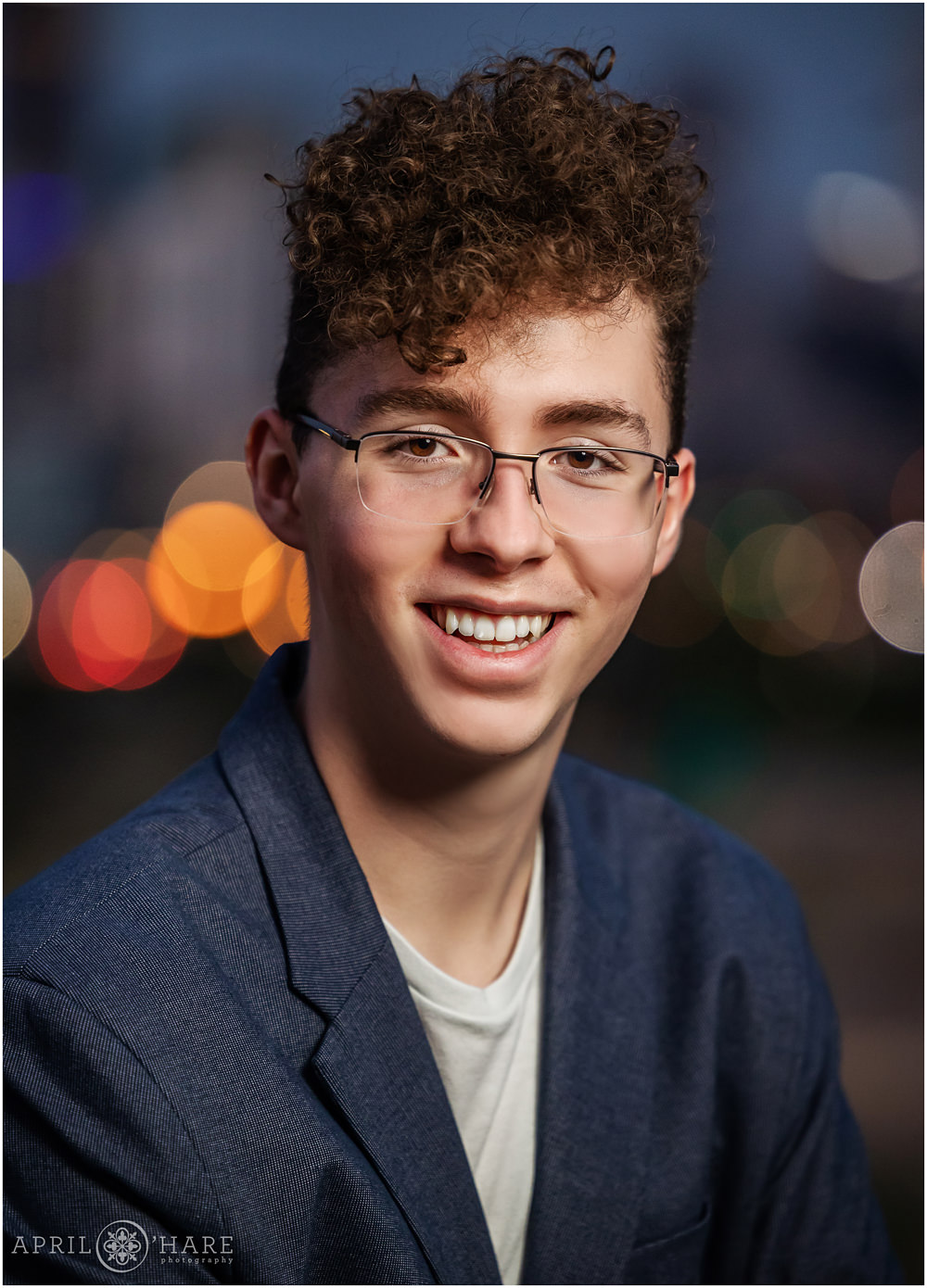 High School senior boy portrait with glowing city lights backdrop in Denver Colorado