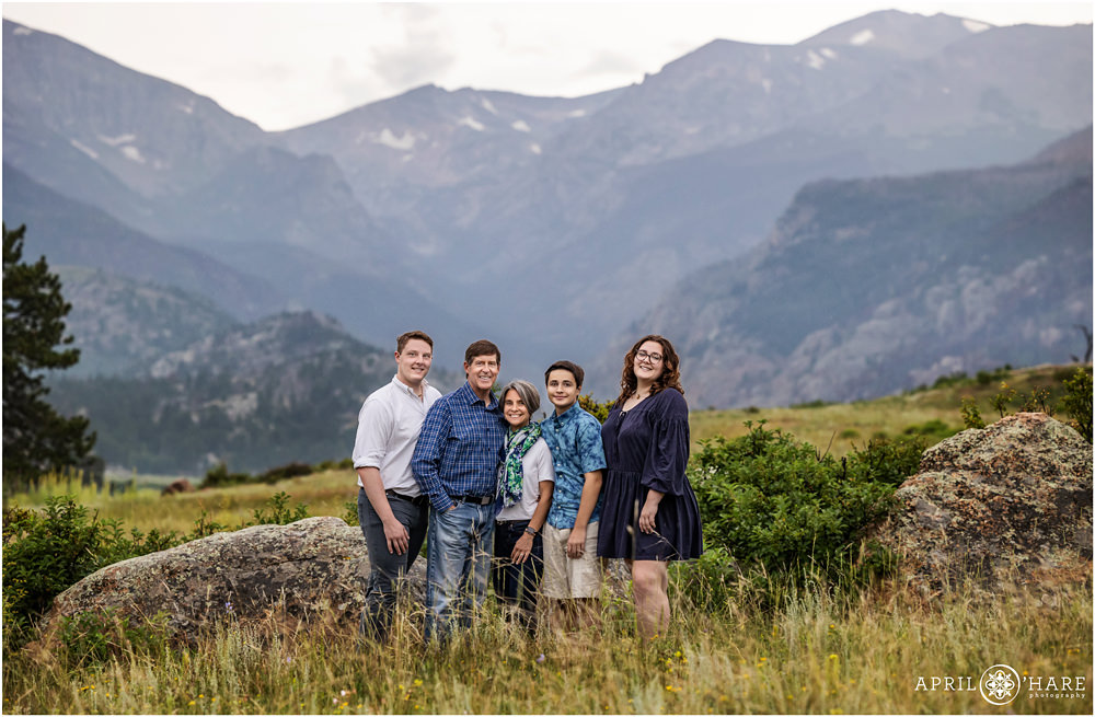 A family of 5 wearing shades of blue pose with the beautiful mountains of Moraine Park in the backdrop during their Estes Park Colorado family portrait session during summer