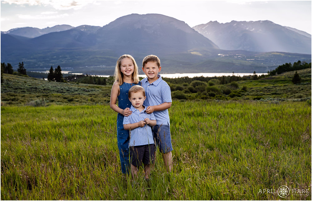3 young siblings pose for a photo in front of a pretty mountain view in Colorado