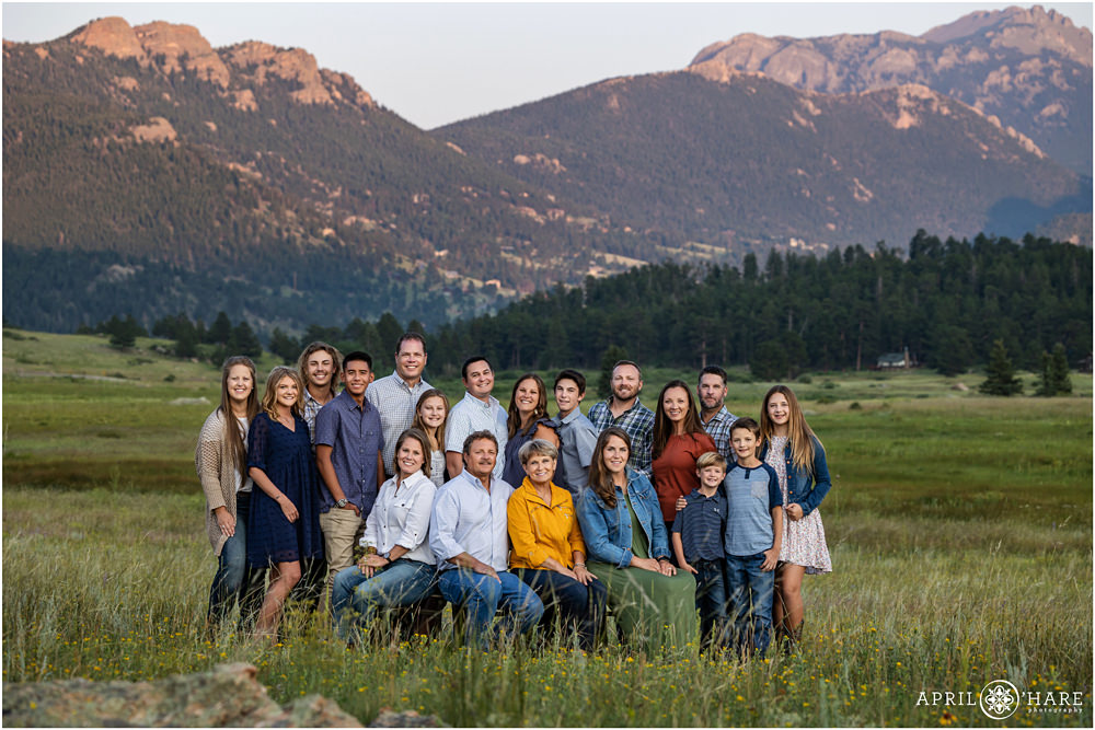 A large extended family pose for a classic portrait together with a pretty sunset mountain view at Rocky Mountain National Park