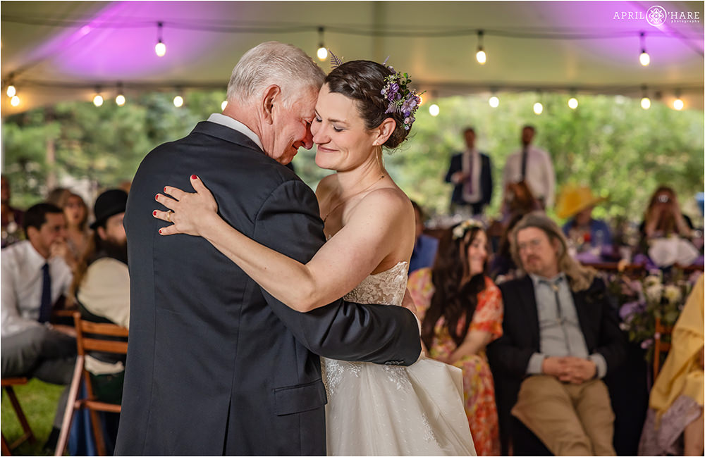 Bride dances with her dad underneath a white tent at Estes Park Condos