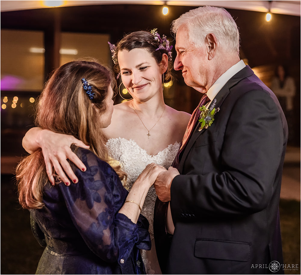 Bride dances with her parentsat her outdoor wedding reception at Estes Park Condos