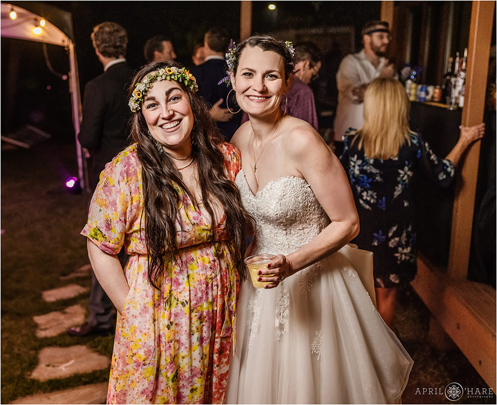 Bride and her friend candidly smile for the camera at an outdoor wedding reception in Colorado