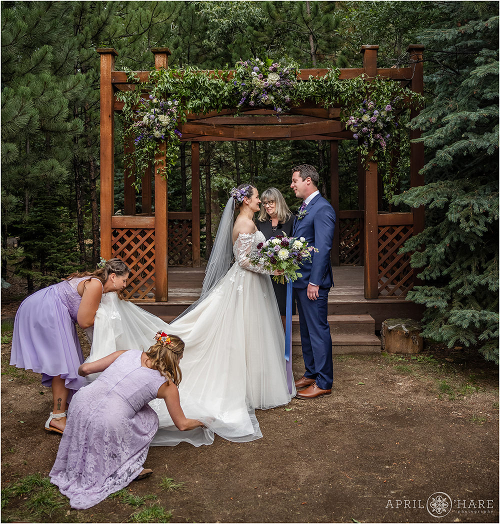 Bohemian bride with flowers in her hair gets help with her wedding train from her friends at Estes Park Condos