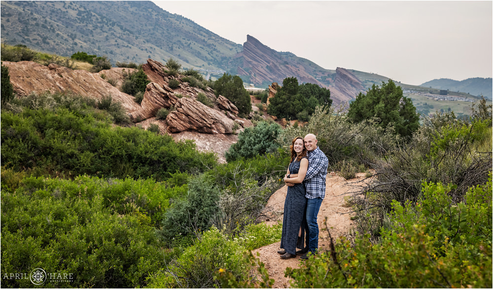 Cute couple wearing blue and boots photographed with pertty red rocks backdrop at East Mount Falcon Trailhead in Morrison Colorado