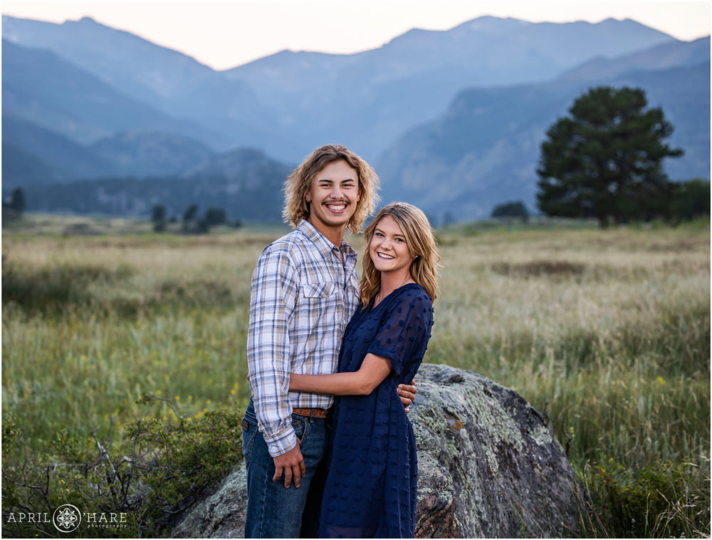 A cute young couple pose in front of a pretty mountain view together while at their family photography session in Estes Park