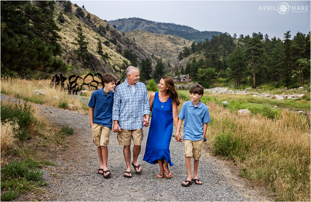 Family of four with twin sons all wearing blue walk along the path at Viestenz-Smith Mountain Park at their family portrait session in Loveland Colorado