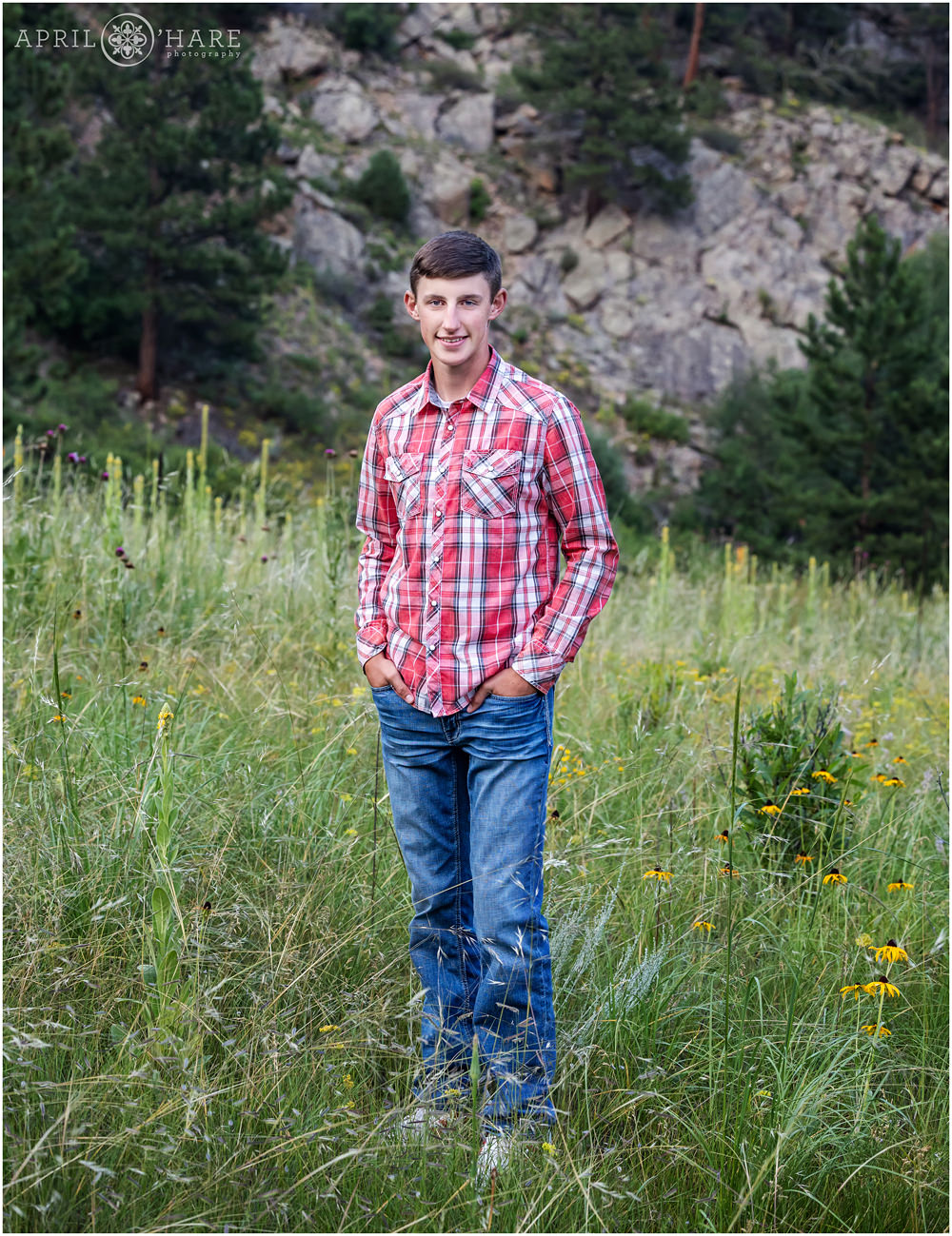 Senior Boy portrait in the wildflower field with rocky backdrop in Boulder mountains