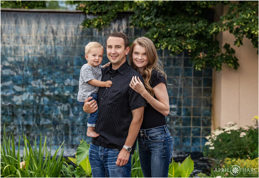Family of 3 pose in front of a pretty blue tiled fountain at Denver Botanic Gardens in Colorado