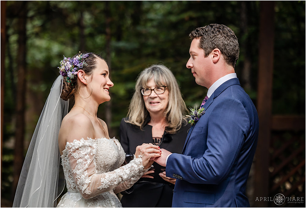 Bride puts ring on groom's finger at their outdoor wedding at Estes Park Condos