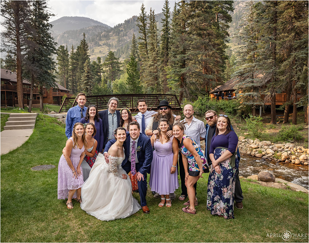 Bride and groom pose for a casual photo with their friends in front of the bridge and Fall River mountain backdrop at Estes Park Condos