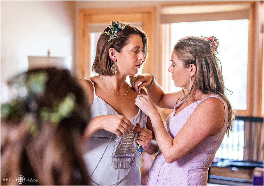 Friends help each other with their dresses at Estes Park Condos on a summer wedding day