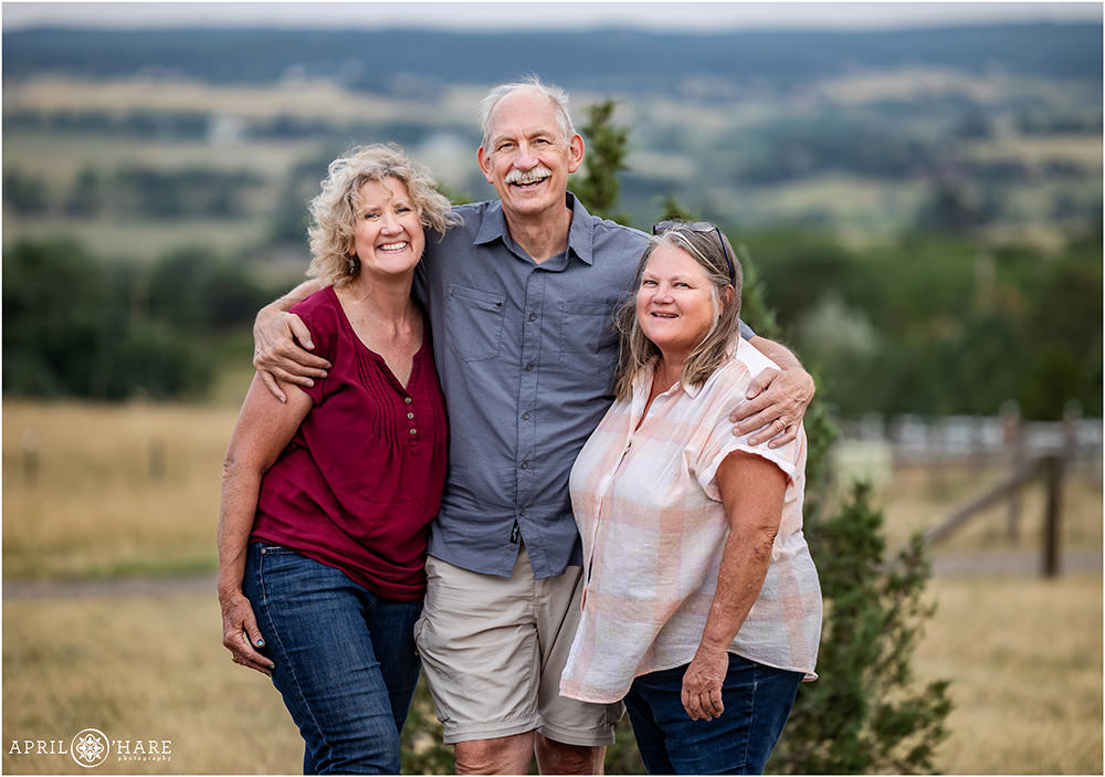 Three adult siblings pose for a photo together at their family reunion on ranch land in Elizabeth Colorado