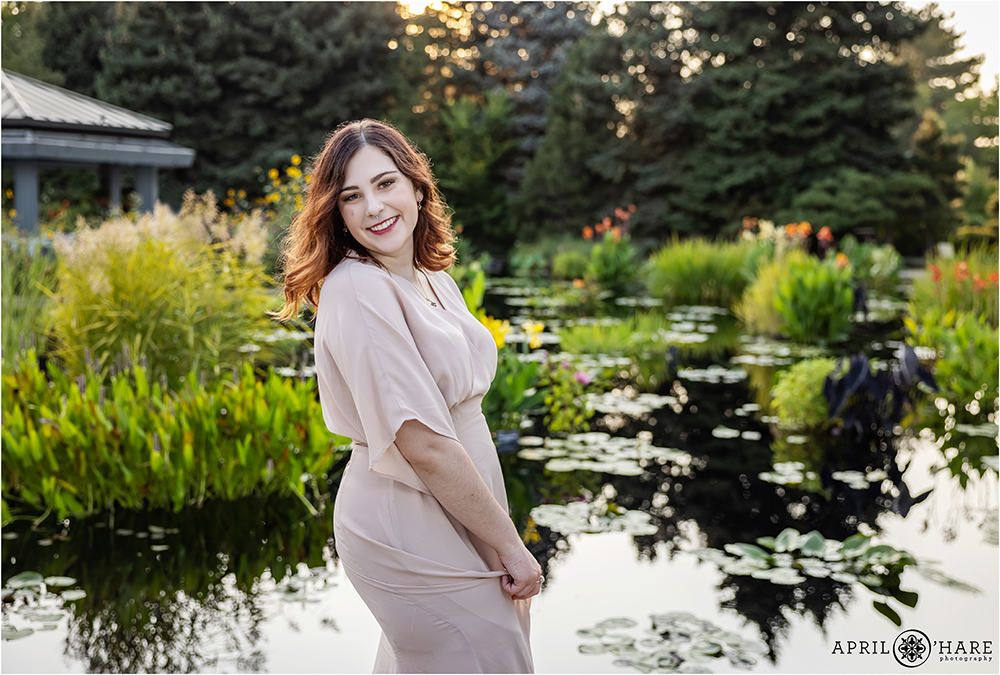A senior girl twirls her dress in front of Monet's Waterlily Garden area of Denver Botanic Gardens