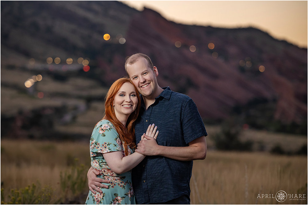 Red Rocks Lit up at Night in the backdrop for a couple's engagement photos at East Mount Falcon Trailhead