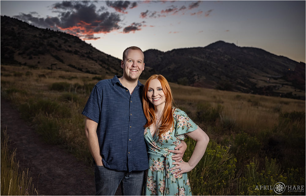 Couple poses for a portrait at dusk with the last bit of sunset sky overhead at East Mount Falcon in Morrison Colorado