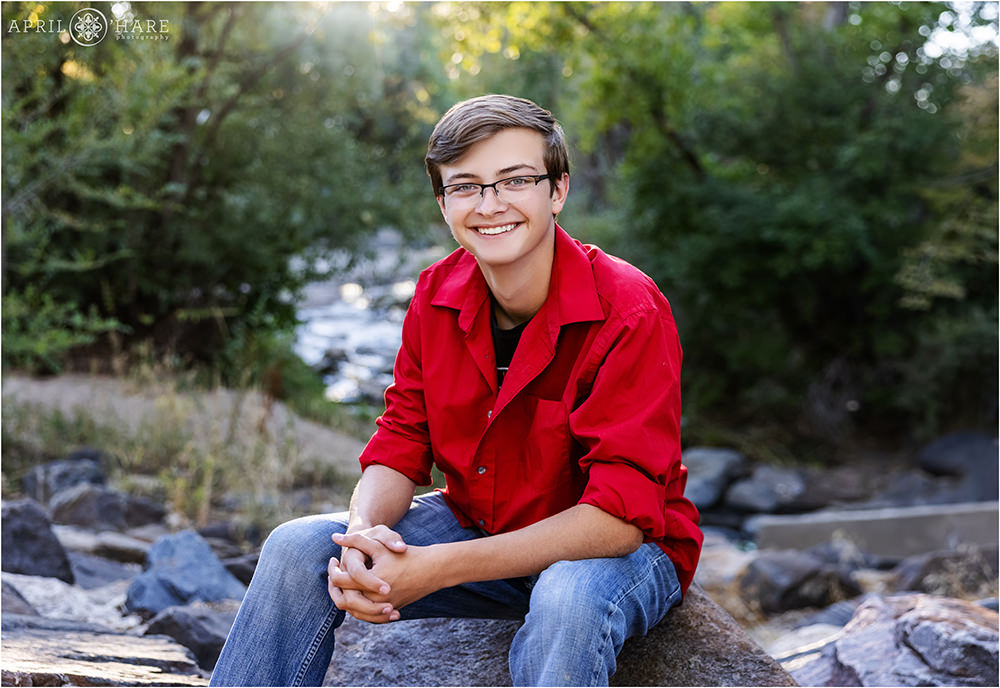 High school senior boy at the Chery Creek Trail near Four Mile House wearing glasses and a dark red button down shirt with the sleeves rolled up