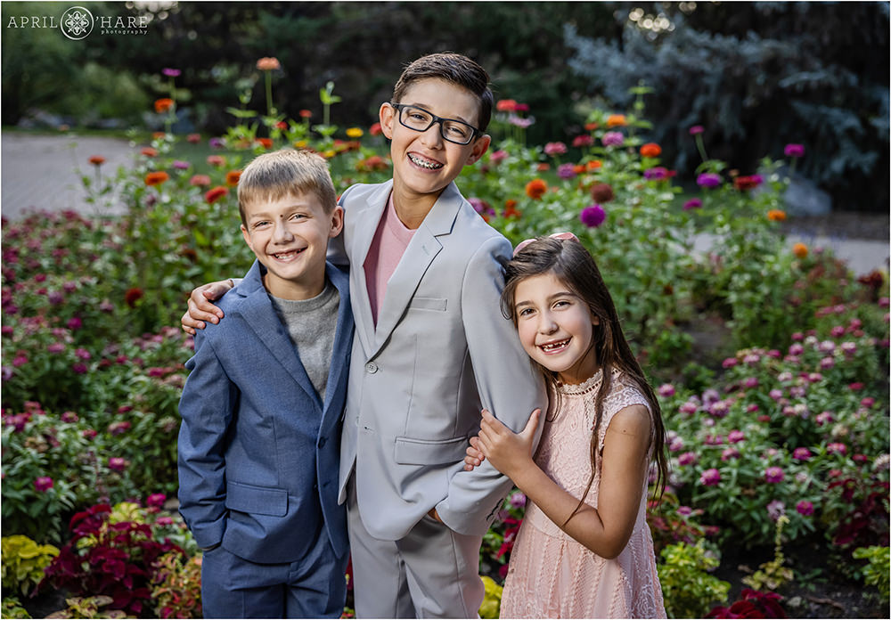 Two big brothers and their little sister smile together for their family photos at Gallup Gardens in Littleton Colorado