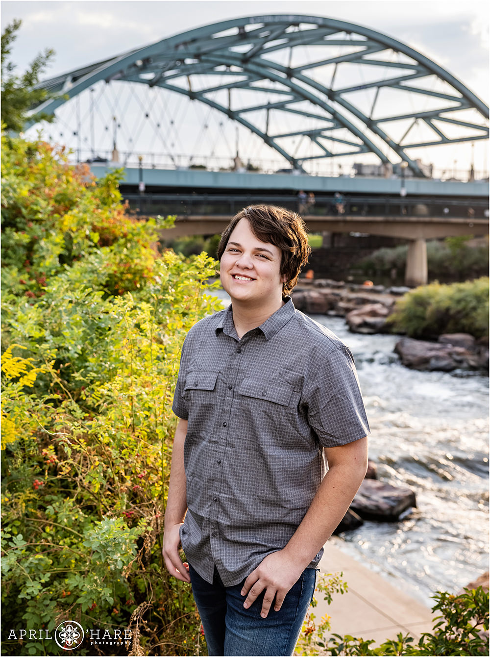 High school senior boy with South Platte River and Speer Bridge in the backdrop senior portrait in Colorado