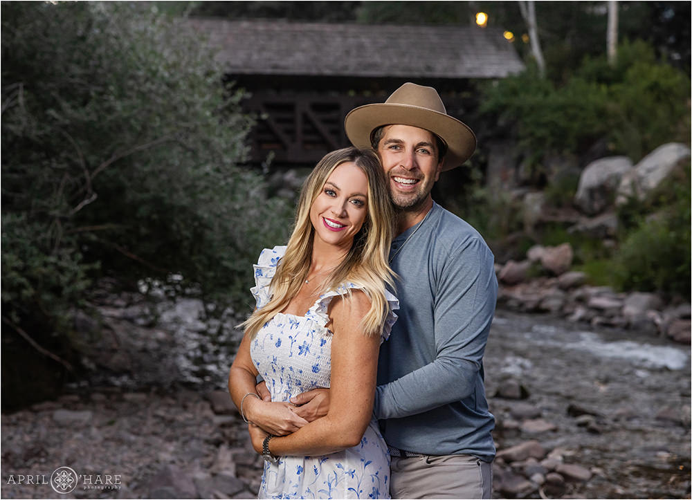 Couples portrait with the Covered Bridge and Gore Creek in the backdrop during summer in Vail Colorado