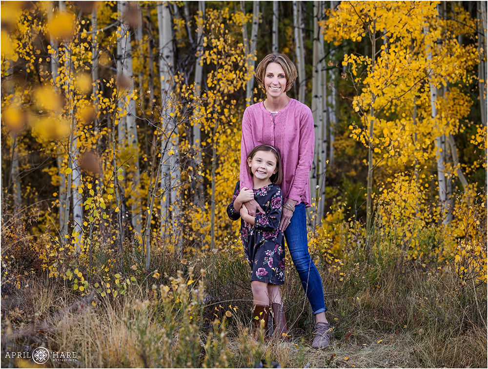 A sweet photo of a mom with her daughter standing together in the gorgeous fall color scenery in Summit County +