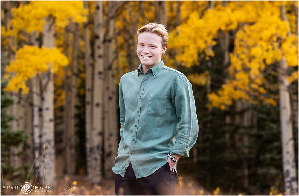 Colorado high school senior boy wearing a green button up shirt with aspen tree backdrop during autumn in Colorado