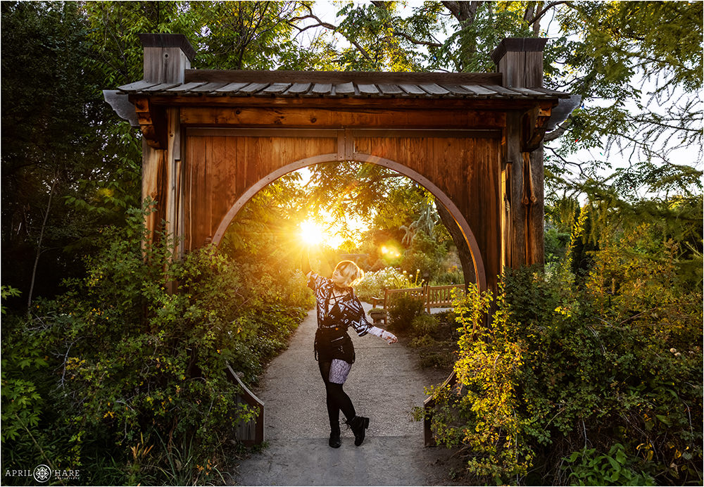 Creative senior portrait in front of the Japanese Circle Gate with sun shining through at Denver Botanic Gardens