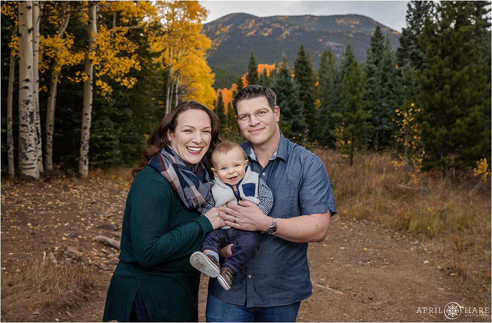 Happy family photos with a smiling baby boy in the golden fall color of Evergreen Colorado