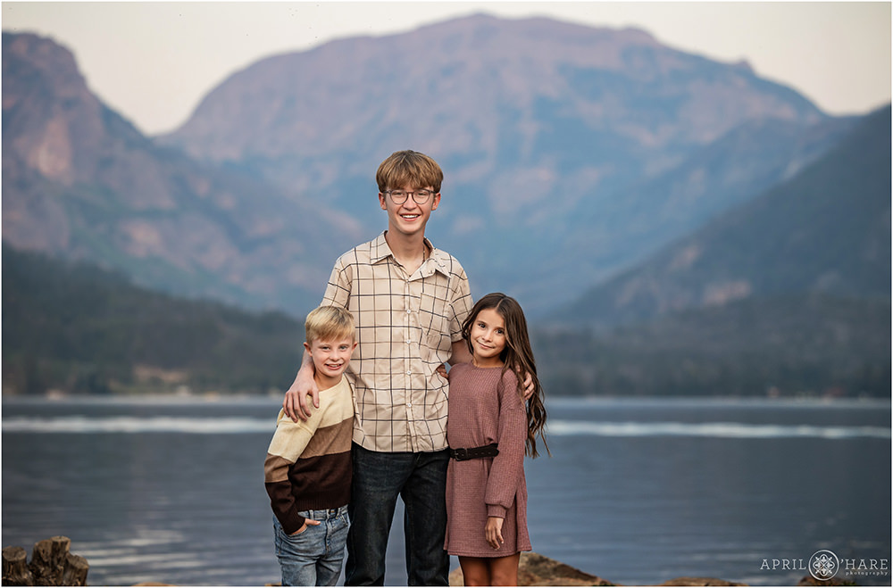 3 siblings pose for photos in front of a beautiful round mountain backdrop in Grand Lake Colorado