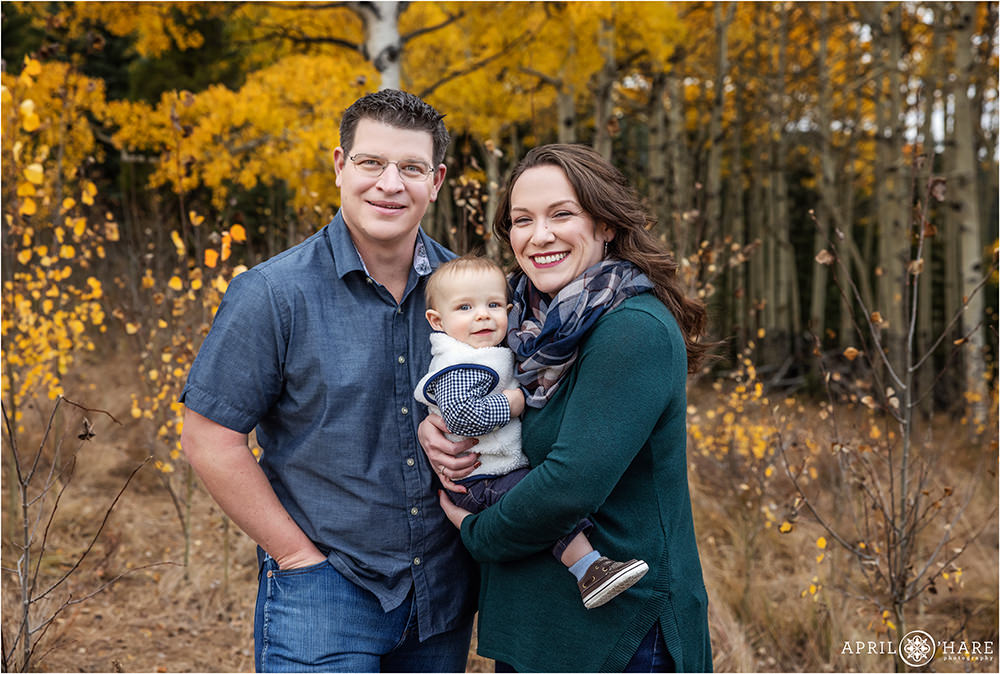 Cute baby boy smiling with his parents at their family photos with the fall color