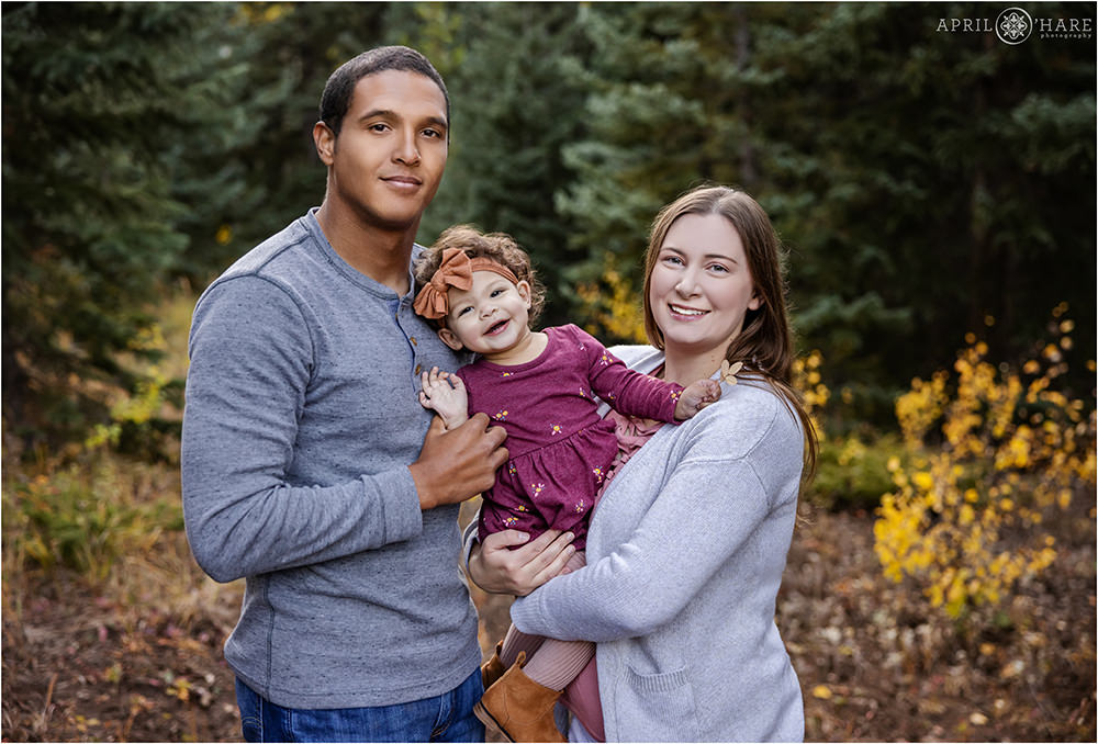 A cute family of 3 in a forest of Colorado during fall color season