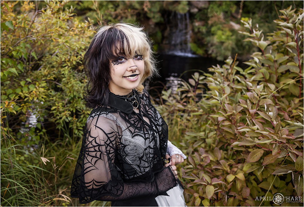 Pretty high school girl with a unique style poses in a fall colored garden setting with a waterfall backdrop at Denver Botanic Gardens