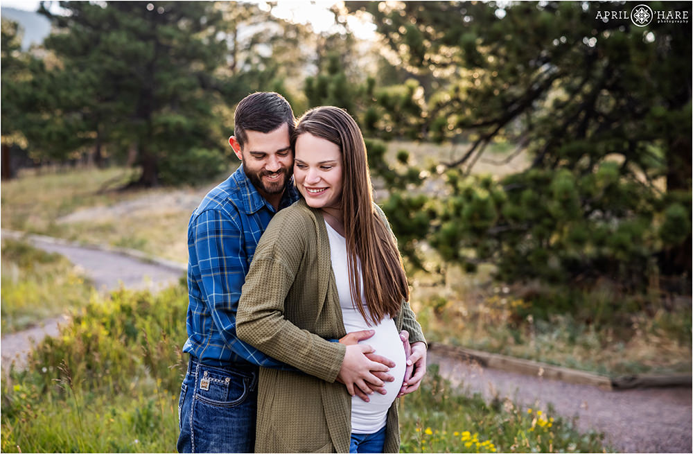 A cute couple snuggle each other for a maternity portrait at their extended family photography session in Estes Park