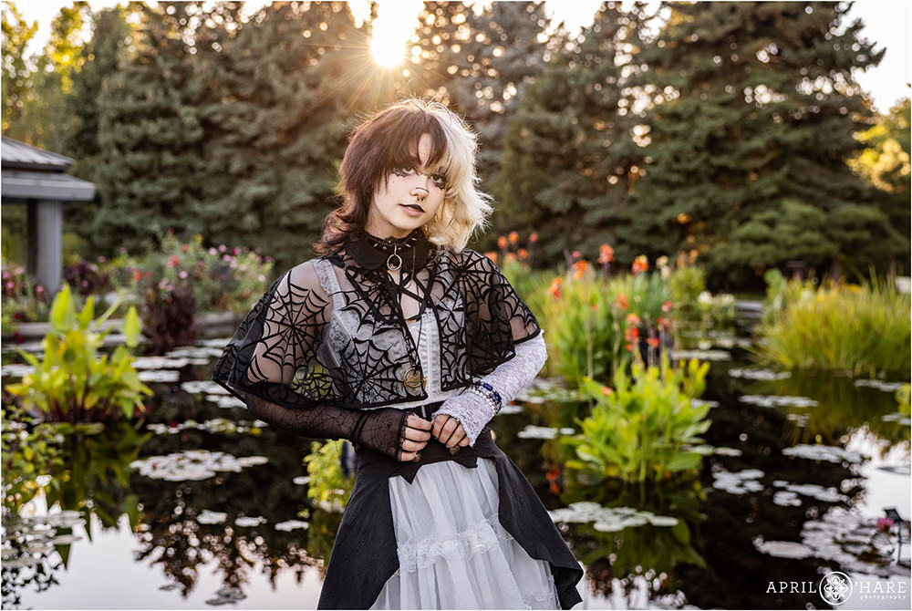 Senior girl with a B&W outfit poses in front of a colorful waterlily garden backdrop at Sunset