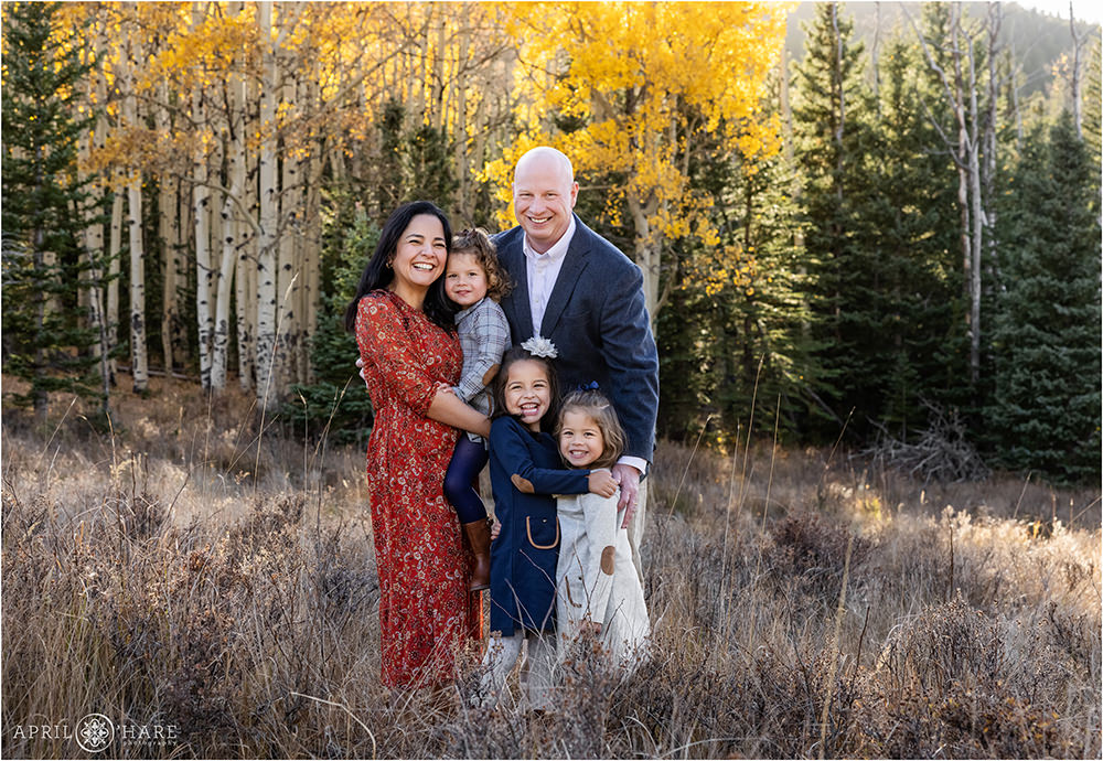 Adorable family of 5 with 3 young daughters stand in a beautiful Colorado mountain meadow
