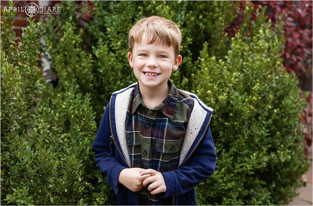 Cute photo of a young boy wearing a blue jacket in the garden at home in Denver